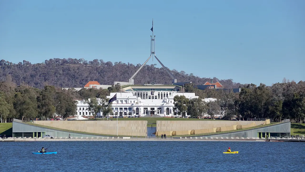Parliament House ใหม่ (ด้านหลัง) กับ Old Parliament House (ด้านหน้า) มองข้ามทะเลสาบ Burley Griffin ภาพจาก Wikimedia Commons ผู้ถ่าย Thennicke สัญญา CC BY-SA 4.0 ไม่ระบุปีที่ถ่าย