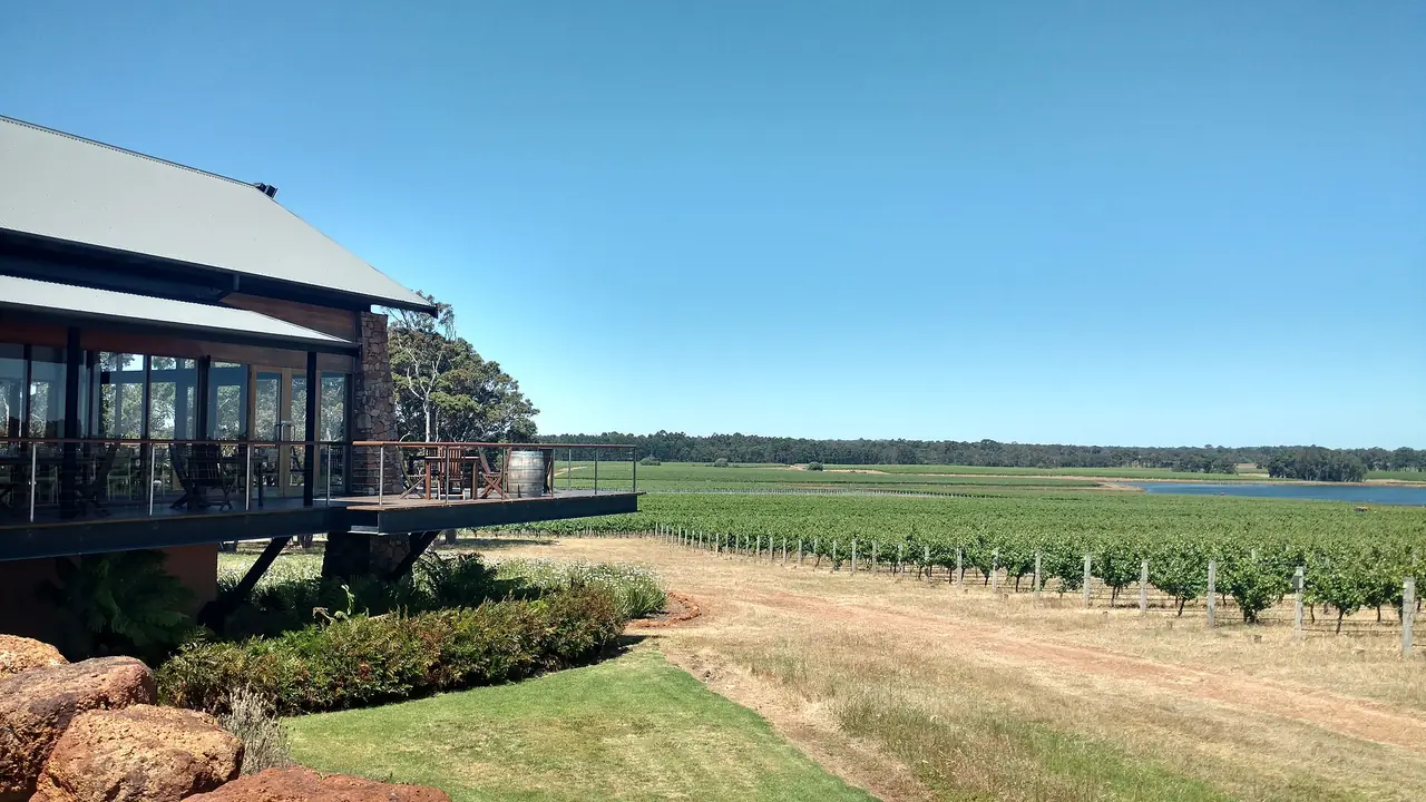 ไร่องุ่นและอาคารชิมไวน์ที่มีระเบียงมองเห็นแถวองุ่นกับทะเลสาบในภูมิภาค Margaret River ชื่อไฟล์ใน Commons ระบุ Watershed vineyard ภาพจาก Wikimedia Commons ผู้ถ่าย Lasthib สัญญา CC BY-SA 4.0 ถ่ายปี 2016