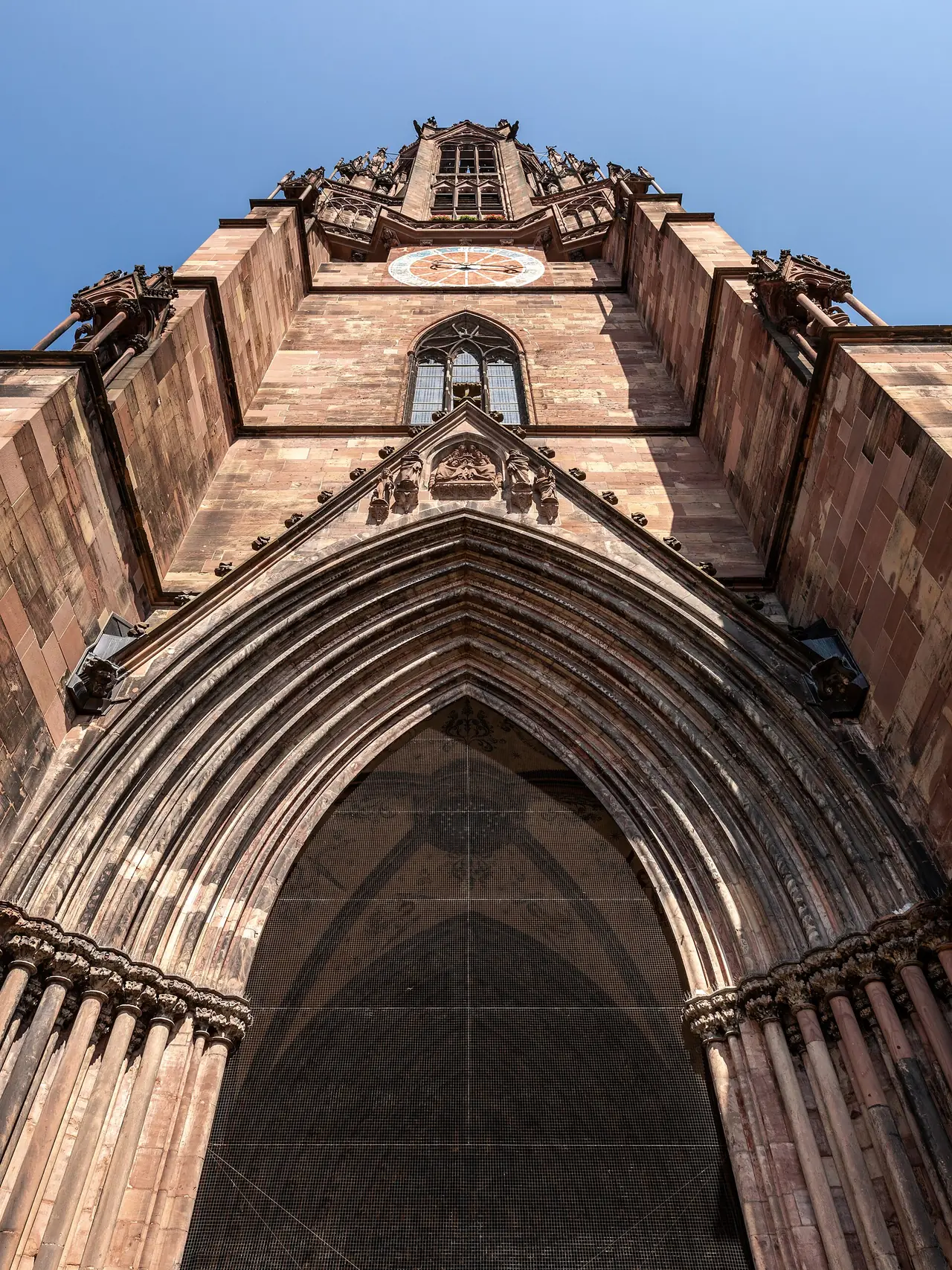 ประตูโค้งและหอของ Freiburger Münster มองจากด้านล่าง ภาพจาก Wikimedia Commons ผู้ถ่าย Dietmar Rabich สัญญา CC BY-SA 4.0 ถ่ายปี 2568