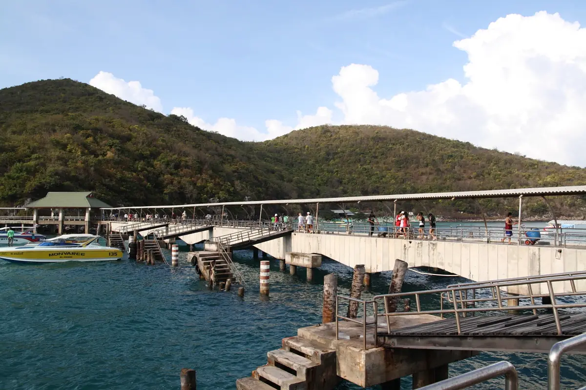 ท่าเทียบเรือบนเกาะล้านที่มีสะพานคอนกรีตยาวและหลังคาคลุมทางเดิน ภาพจาก Wikimedia Commons ผู้ถ่าย Ilya Plekhanov สัญญา CC BY-SA 3.0 ชื่อไฟล์ว่า Koh Lan Pier ไม่ระบุว่าท่าไหนระหว่างหน้าบ้านกับตาแหวนและไม่ระบุปีที่ถ่าย