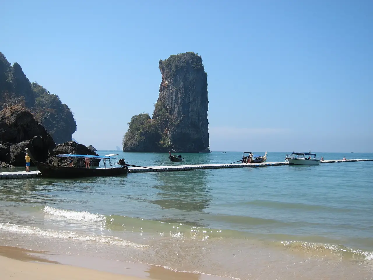 อ่าวไปป่องมีแพลอยสำหรับเรือเข้าฝั่ง และหินปูนยอดสูงอยู่กลางน้ำใกล้ชายหาด ภาพจาก Wikimedia Commons ผู้ถ่าย Jukka from HELSINKI, Finland สัญญา CC BY 2.0 ตามคำบรรยายไฟล์ไม่ระบุปีที่ถ่าย เป็นภาพประกอบ ที่พักและสิ่งปลูกสร้างอาจเปลี่ยนไปแล้ว