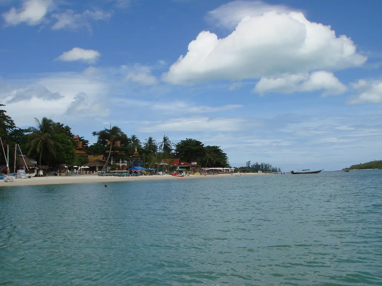 ชายหาดและแนวร่มไม้ริมอ่าวที่ Commons ติดป้ายว่าหาดเฉวง เกาะสมุย ภาพจากมุมทะเลมองเข้าฝั่ง เราไม่ทราบว่าเป็นช่วงไหนของหาด จึงใช้เป็นภาพประกอบบรรยากาศ ภาพจาก Wikimedia Commons ผู้ถ่าย zoomion.ch สัญญา CC BY-SA 3.0