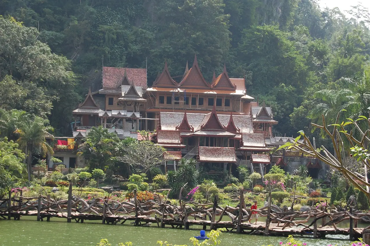 อาคารไม้ทรงไทยหลายชั้นริมสระน้ำ มีสะพานไม้ท่อนธรรมชาติพาดอยู่ด้านหน้า ชื่อไฟล์ Wat Kao Wong01 ภาพจาก Wikimedia Commons ผู้ถ่าย Meneerke bloem สัญญา CC BY-SA 3.0 ไม่ทราบปีที่ถ่าย